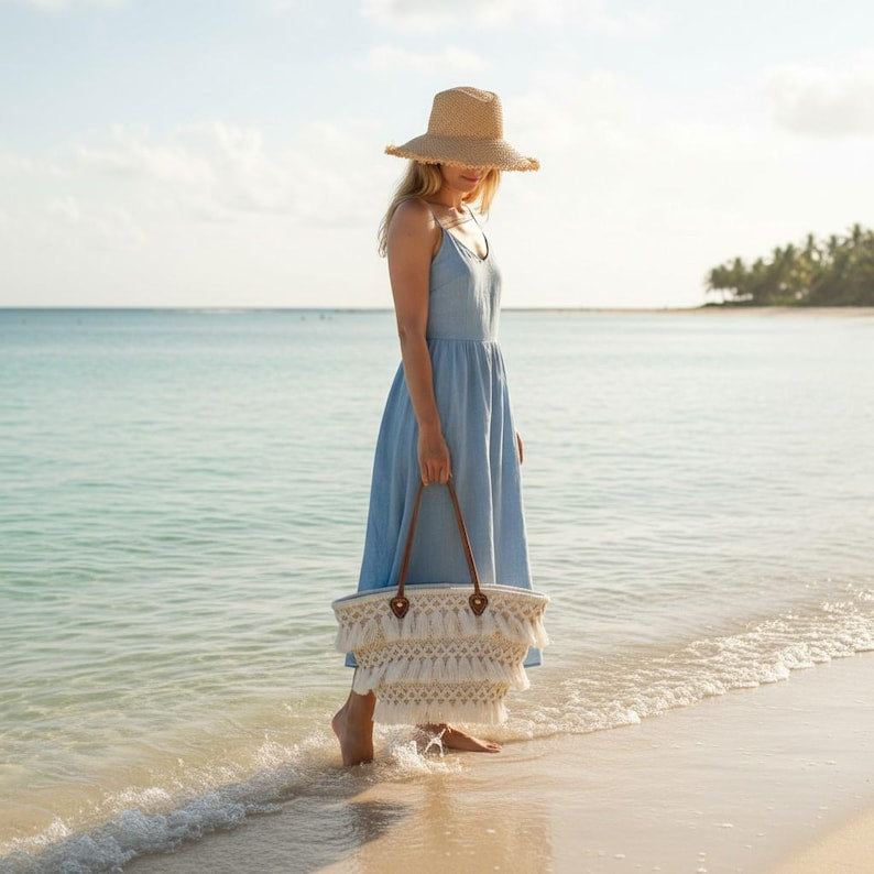 Bohemian straw tote with macramé fringe worn with blue dress and straw hat